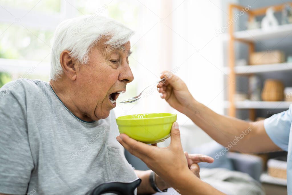 Hungry Elder Patient Being Feed At Nursing Home