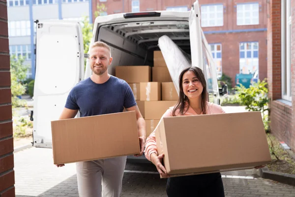 Couple Moving Boxes From Van Or Truck Together Outdoors