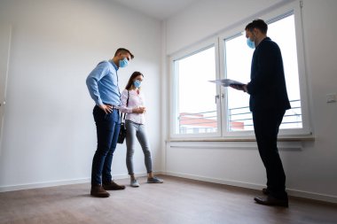 Mutlu çift emlakçı maskeli yeni bir ev alıyor.