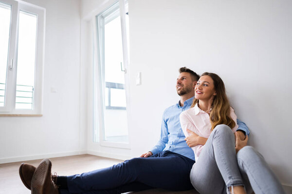 Young Happy Couple Thinking And Dreaming In New House