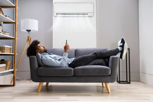 Jovem Deitado Sob Condicionado Sofá Usando Smartphone Casa — Fotografia de Stock