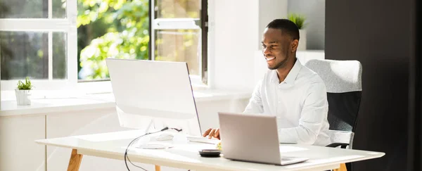アフリカ系アメリカ人男性がオフィスでコンピュータに座っている — ストック写真
