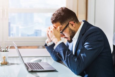 Migreni olan mutsuz üzgün adam dizüstü bilgisayar kullanıyor