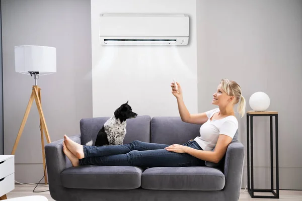 Gelukkige Vrouw Zittend Bank Met Behulp Van Airconditioning Thuis — Stockfoto