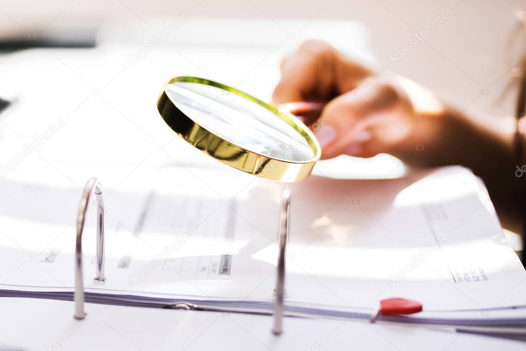 Business Auditor Using Magnifying Glass For Paperwork Fraud Investigation