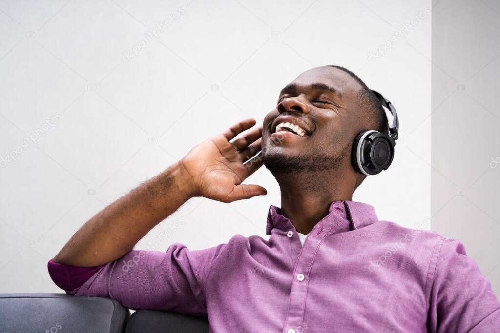 Happy African American Man Enjoying Music Through Headphones In At Home