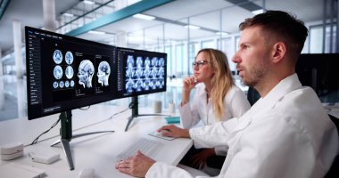Kadın doktor, Radyoloji yazılımını kullanarak hastanın beynini izliyor.