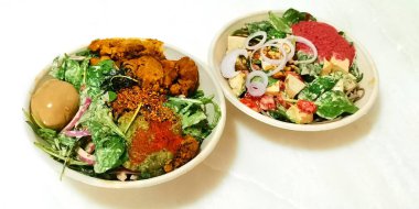 Salata, iki kase sağlıklı salata yanında da Rendang tavuğu, yumurta, havyar, soğan, sebze ve beyaz üzerine izole edilmiş elbise.