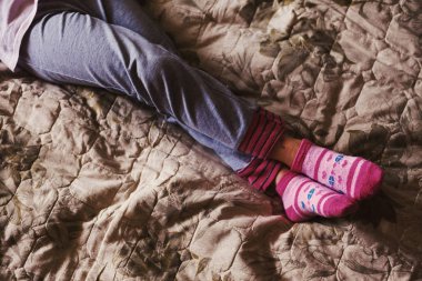 Yatakta dinleniyor küçük bir kızın bacakları. 