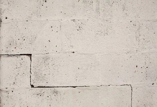 Texture of an old wall, big bricks painted in white with one crack on one side.