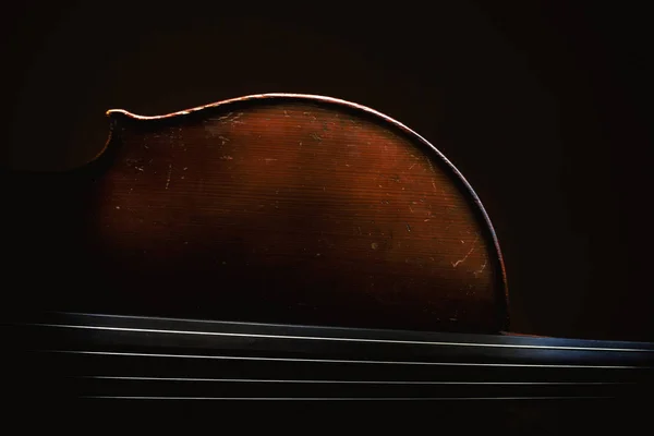 旧的尘土飞扬的大提琴的一部分 旧的木材和字符串的细节 强调在黑暗中的形状 — 图库照片
