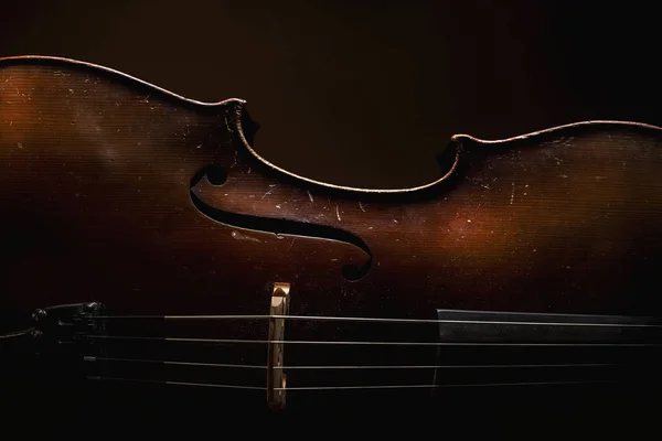 旧的尘土飞扬的大提琴的一部分 旧的木材和字符串的细节 强调在黑暗中的形状 — 图库照片