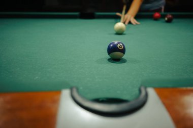 Bir oyuncu bir sonraki hamlesini bir gece barında büyük bir bilardo masasında yapmaya hazırlanıyor..