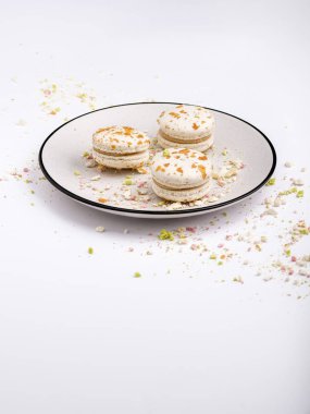 Mavi kenarlıklı beyaz tabakta çok renkli kırıntı üç bej beyaz acıbadem kurabiyesi kurabiye. Gıda arka plan, sığ Dof, yumuşak odak, kopyalama alanı.