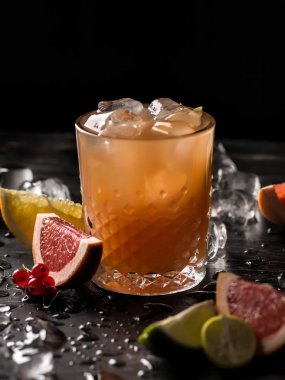 Bardak portakal suyu ve meyve dilimleri (portakal, greyfurt, limon ve Frenk üzümü) siyah arka plan üzerine buzla. Yakın çekim, sığ Dof, yumuşak odak.