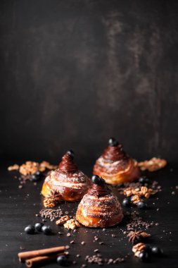 Tatlı çörekler krem çikolata, baharatlar ve meyveleri koyu arka plan üzerinde. Atölye çekilen fotoğraf. Seçici odak, sığ Dof, kopya alanı.