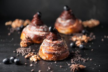 Tatlı çörekler krem çikolata, baharatlar ve meyveleri koyu arka plan üzerinde. Seçici odak, sığ Dof. Fotoğraf Atölyesi.
