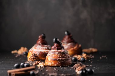 Tatlı çörekler krem çikolata, baharatlar ve meyveleri koyu arka plan üzerinde. Seçici odak, sığ Dof. Fotoğraf Atölyesi.