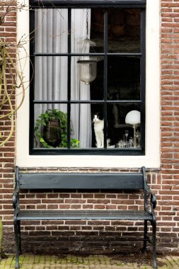 Pencere kenarında oturan ve pencerenin altında bir Bank ile küçük ev pencere bakarak kedi.