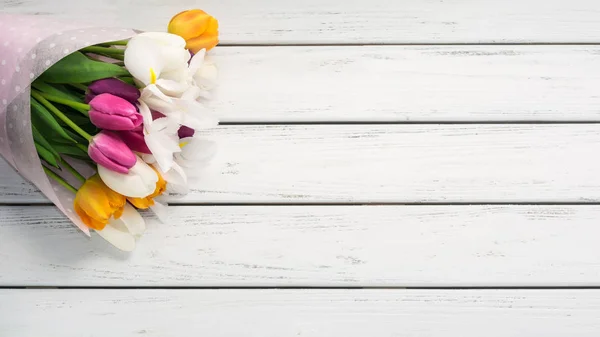 白い木製のテーブルに紙のラッパーで色とりどりのチューリップの花束 コピー スペース — ストック写真