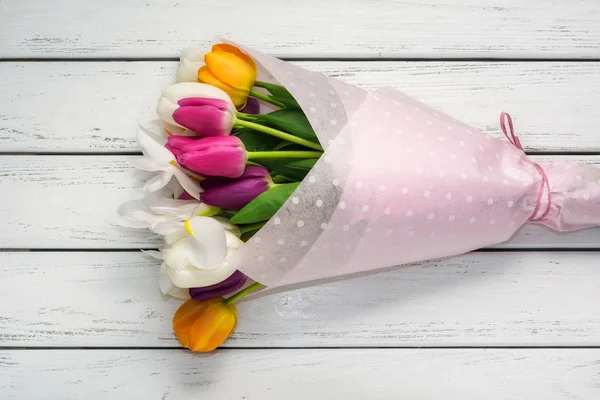 白色木桌纸包装纸上的五颜六色的郁金香花束 — 图库照片