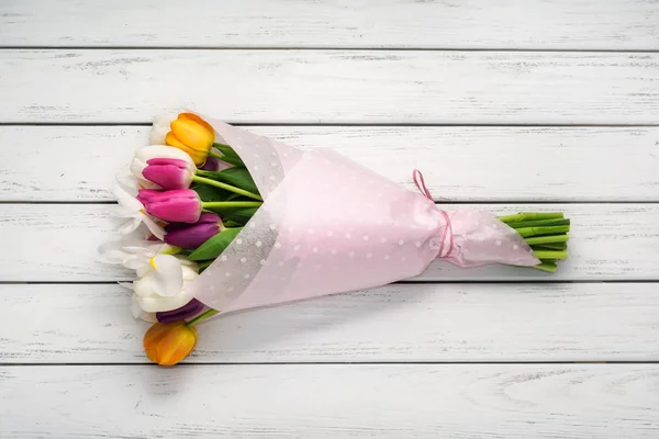 白色木桌纸包装纸上的五颜六色的郁金香花束 — 图库照片