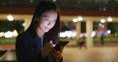 Kadın geceleri smartphone şehir içinde bak 