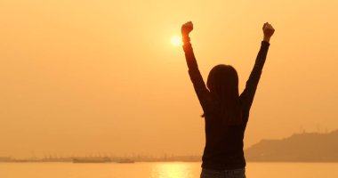 Woman raising hand up under sunset  clipart