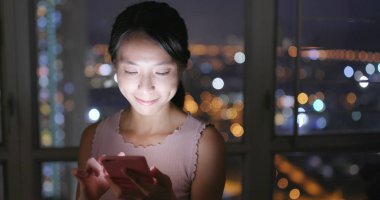 Evde akıllı telefon kullanan bir kadın.