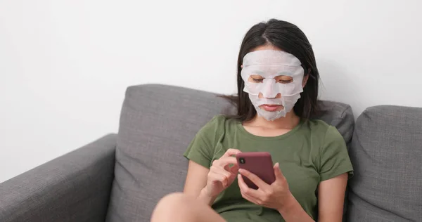 Perempuan Menerapkan Masker Wajah Dan Menggunakan Ponsel Rumah — Stok Foto