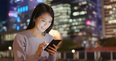 Genç kadın cep telefonuyla şehirde geceleri 