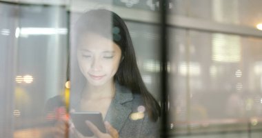 Pencere yansıması ile şehirde Smartphone kullanarak iş kadını