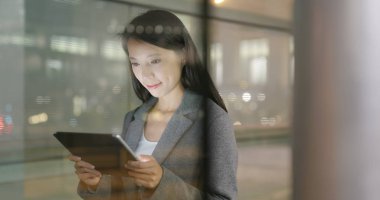 Pencere rağmen geceleri tablet bilgisayar kullanarak iş kadını