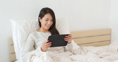 Kadın iş yatağa üzerinde tablet bilgisayarda