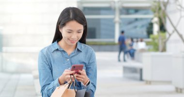 Genç kadın alışveriş çantası ile istimal hareket eden telefon 