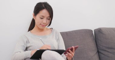 Kadın evde cep telefonu ile tablet bilgisayarda çizim