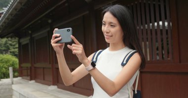 Çin bahçede fotoğraf çekmek için cep telefonu kullanan kadın seyahat