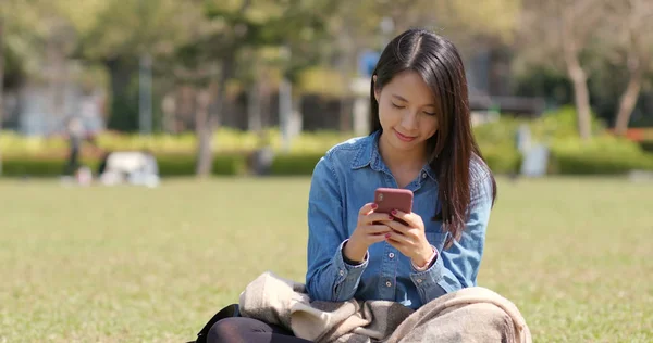 Νεαρή Γυναίκα Χρησιμοποιώντας Κινητό Τηλέφωνο Και Κάθεται Στο Πράσινο Γκαζόν — Φωτογραφία Αρχείου