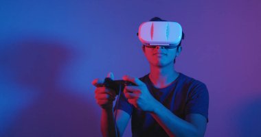 Genç adam oynamak oyun Vr üzerinde kırmızı ve mavi ışık altında 