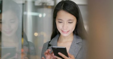 Geceleri pencere yansıması ile cep telefonuyla işkadını