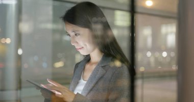 Pencere rağmen geceleri tablet bilgisayar kullanarak iş kadını