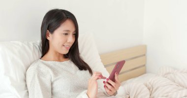 Genç kadın yatakta istimal hareket eden telefon