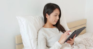 yatağın üzerine tablet bilgisayar kullanan kadın