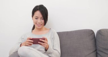 Cep telefonu kullaranarak ve koltukta oturan kadın