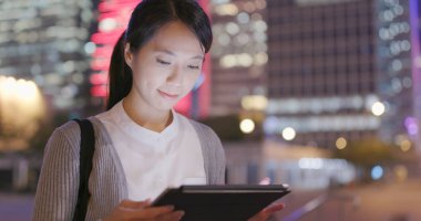 Tablet bilgisayar şehirde geceleri kullanarak iş kadını