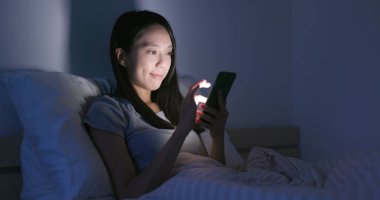 Geceleri cep telefonu kullanan bir kadın.