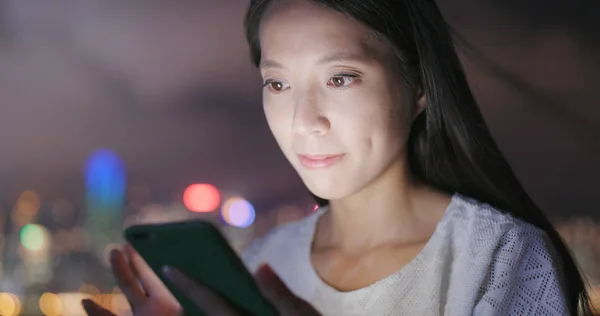 Woman using cellphone for sending audio message in Hong Kong at night