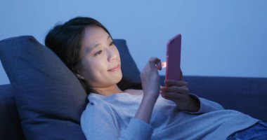 Cep telefonu kullaranarak ve kanepeye uzanmış kadın