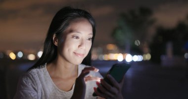 Geceleri cep telefonu kullanan kadın
