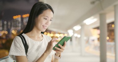 Geceleri cep telefonu kullanan bir kadın.